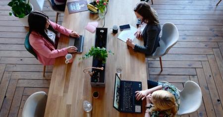 A group of workers at a desk on their laptops