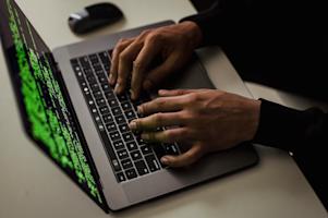 Hands typing on a laptop keyboard.