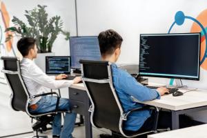 Two people working on their computers at their adjoining desks.