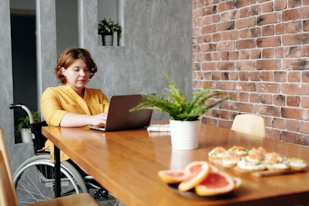 A woman in a wheelchair using her laptop with Splashtop to remotely access her office computer.