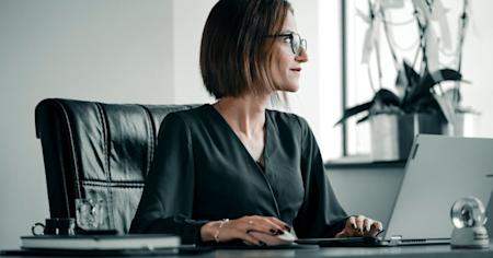 A woman working on a computer at her office desk.