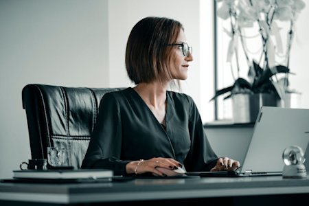 A woman working on a computer at her office desk.