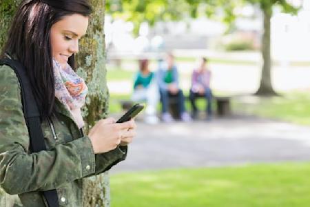 A woman outside at a park using Splashtop on her iPhone to access her remote desktop computer.