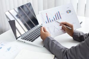 Professional analyzing finance charts with remote access on a laptop.