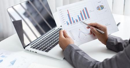 Professional analyzing finance charts with remote access on a laptop.