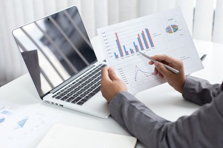 Professional analyzing finance charts with remote access on a laptop.