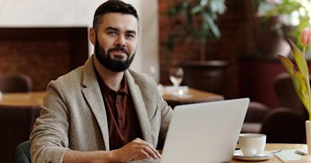 A smiling IT technician at his laptop.