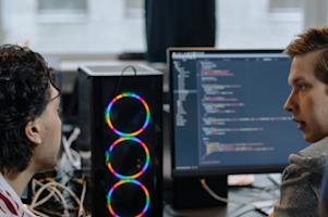 Two IT workers at a workstation.