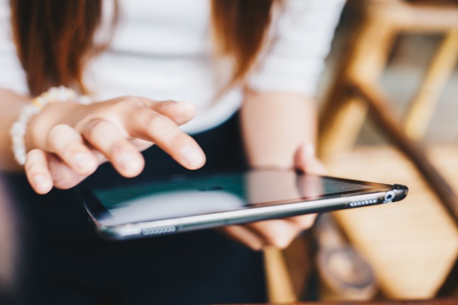 Close-up of a hand using a tablet device, with the focus on the sleek black tablet edge and touchscreen interface.