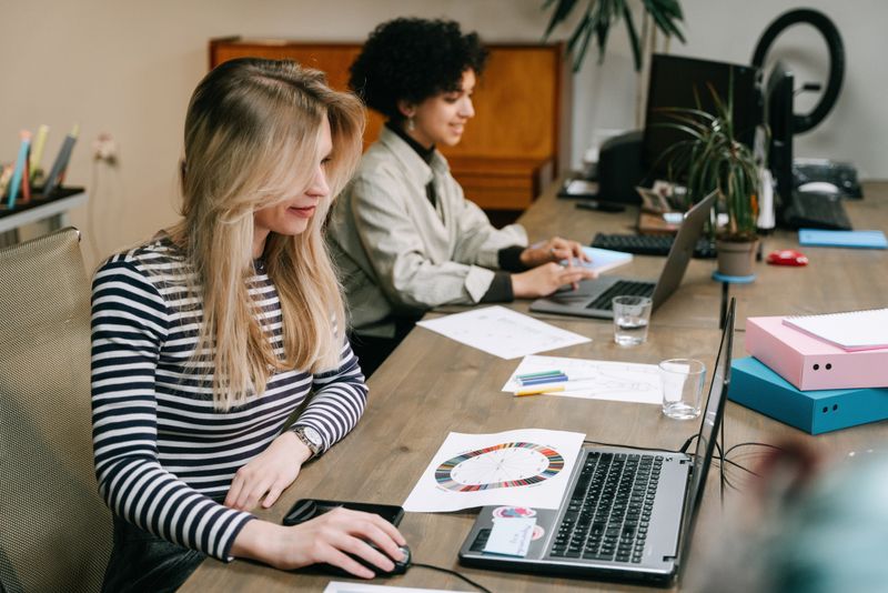 Two people at their office workstations using their computers.