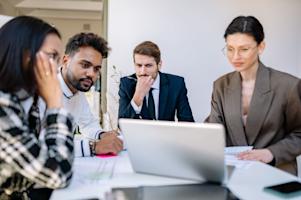 A group of people in a business office looking at a computer screen.