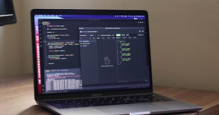 A Mac laptop displaying code for API connectivity on a wooden desktop.