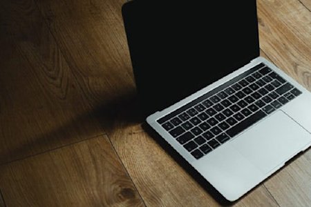 A MacBook air on a wooden floor.