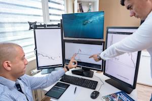 Two businessmen pointing at a chart on a computer screen.