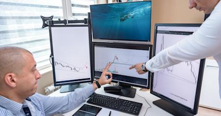 Two businessmen pointing at a chart on a computer screen.