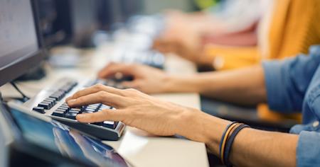 Hands typing on a computer