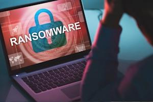 Man looking worriedly at a computer screen with a large notification displaying a ransomware attack