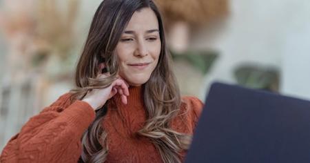 A woman smiling while usign her computer.