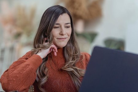 A woman smiling while usign her computer.