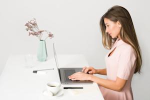 A woman working on a laptop at a desk.