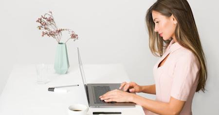 A woman working on a laptop at a desk.