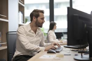 Two people working on their computers in an office.