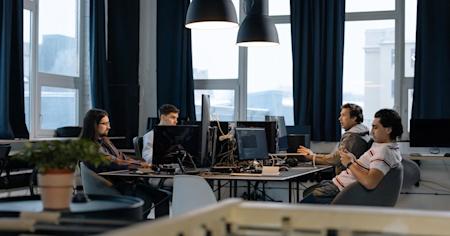 IT workers on their computers at their desks in an office room.