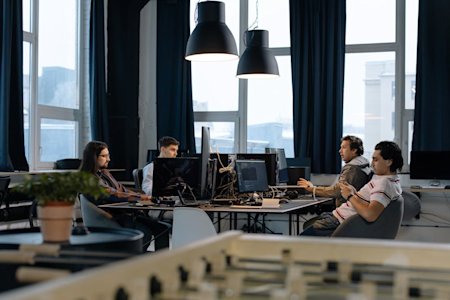 IT workers on their computers at their desks in an office room.