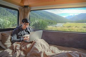 A digital nomad working remotely on his computer in his van.