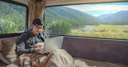 A digital nomad working remotely on his computer in his van.