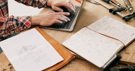 A person in a manfucturing facility types on a laptop.