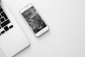 An iPhone and a laptop on a desk.