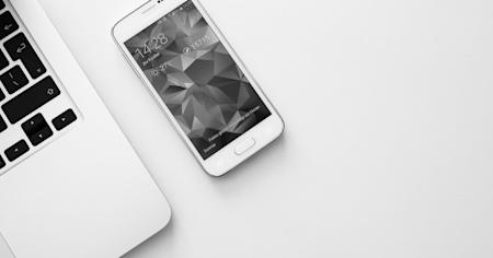 An iPhone and a laptop on a desk.