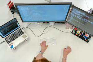 A person using a computer at their office desk.