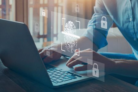 Hands typing on a laptop with a fingerprint scan and security icons.