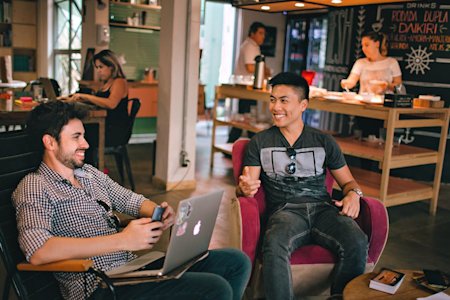 A group of coworkers in a small business office working and smiling.