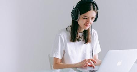 A woman wearing headphones and using Splashtop on her laptop to work remotely.