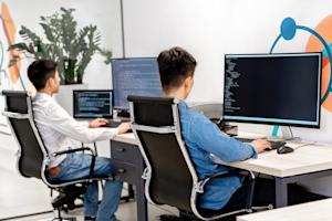 Two co-workers at their desks working on their computers.