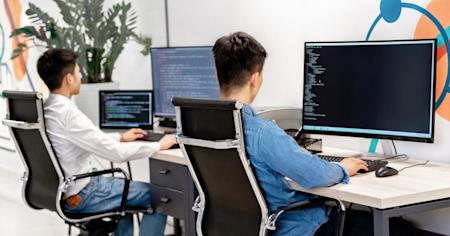 Two co-workers at their desks working on their computers.