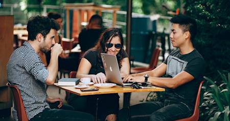 Three professionals collaborating at an outdoor café using Splashtop for efficient workflow