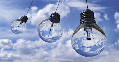 Three light bulbs hanging against a blue sky with clouds