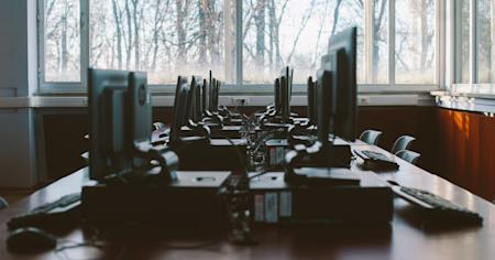 Several computers on a long table in an office.