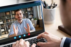 Man on a laptop with a video call on the screen