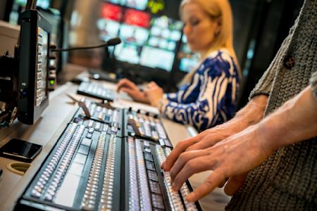 A broadcasting professional typing in a studio room.