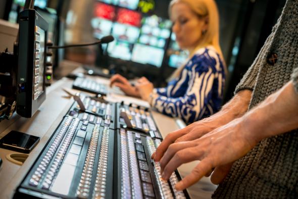 A broadcasting professional typing in a studio room.