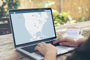 Man using laptop outdoors with a cup of coffee and a screen displaying VPN connection to prevent ransomware