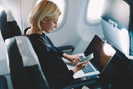 Woman sitting on a plane seat using Splashtop to remotely access a device from her laptop
