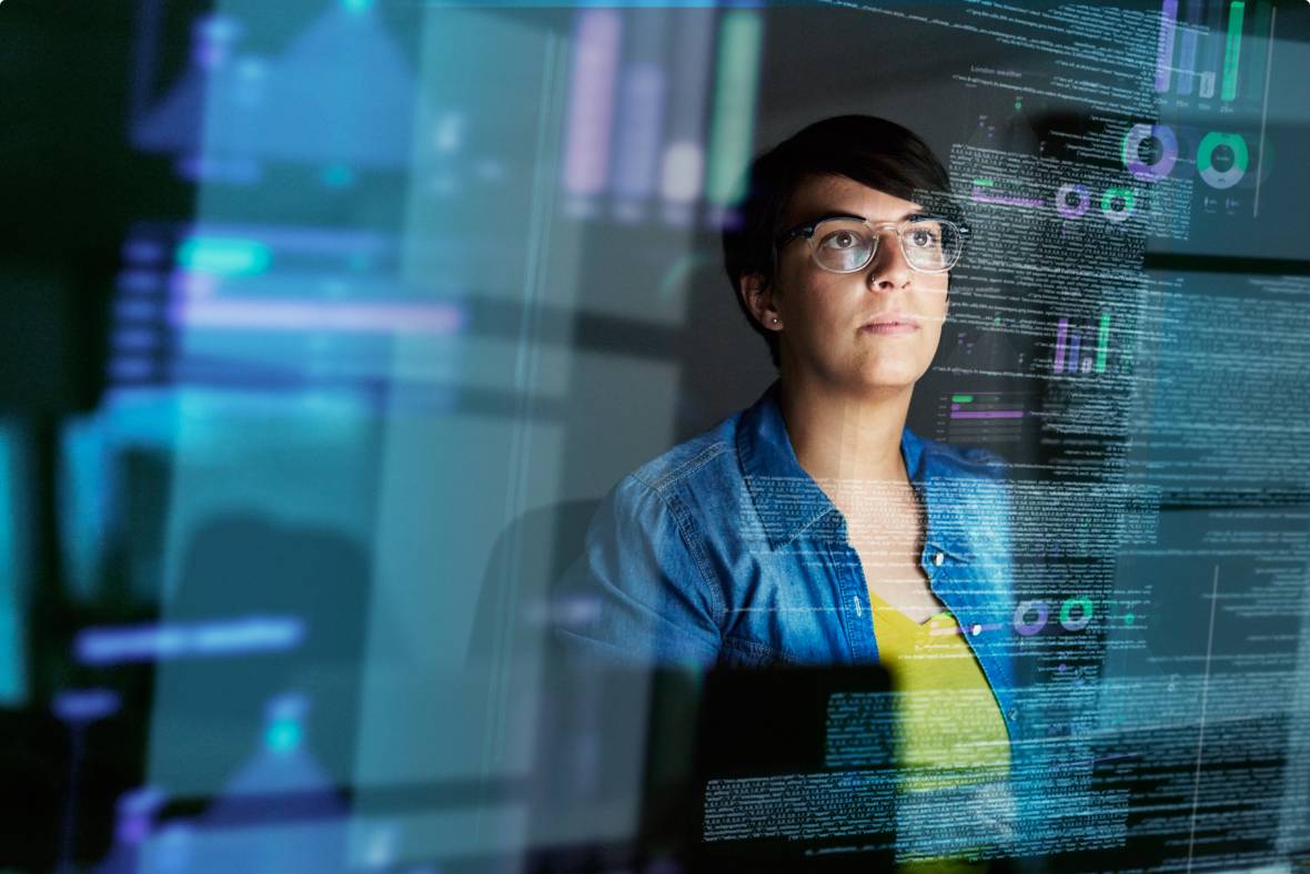 A person wearing glasses looks at multiple transparent digital screens displaying data, charts, and code, suggesting they are analyzing information or working on a tech-related project.