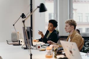 Two coworkers working on their computers in an office.