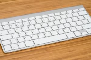 A bamboo desk with a white Apple keyboard resting on it
